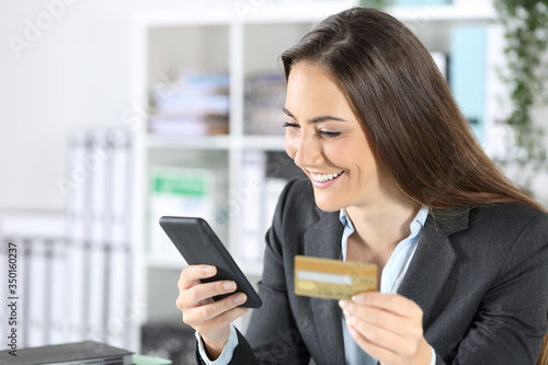 Happy executive paying with card on phone at office