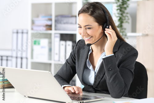 Happy telemarketer with laptop attending call at office