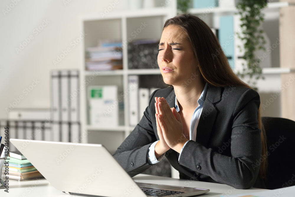 Worried executive with laptop praying at night at office Worried executive with laptop praying at night at office