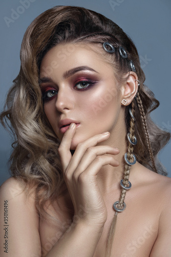 haute couture model with wavy hair and pigtails on the side. beauty shooting, bright evening make-up by an attractive slim young girl. advertising jewelry, white gold and silver. Close-up
