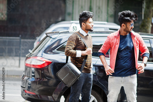 Wallpaper Mural Two young stylish indian man frieds model posing in street against black taxi car. Torontodigital.ca
