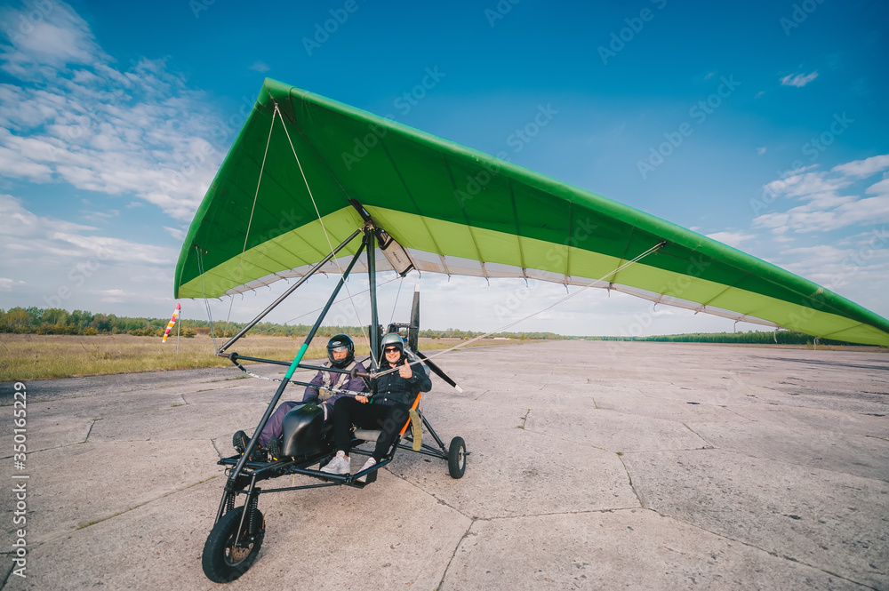 Hang-gliding with two people, standing at dawn on the runway.