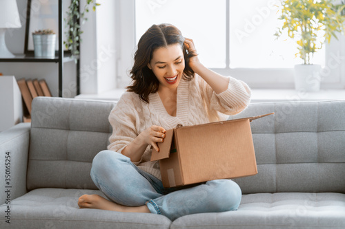 woman is holding cardboard box sitting on sofa at home