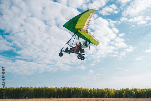 Hang glider pilot makes maneuvers close to the green trees