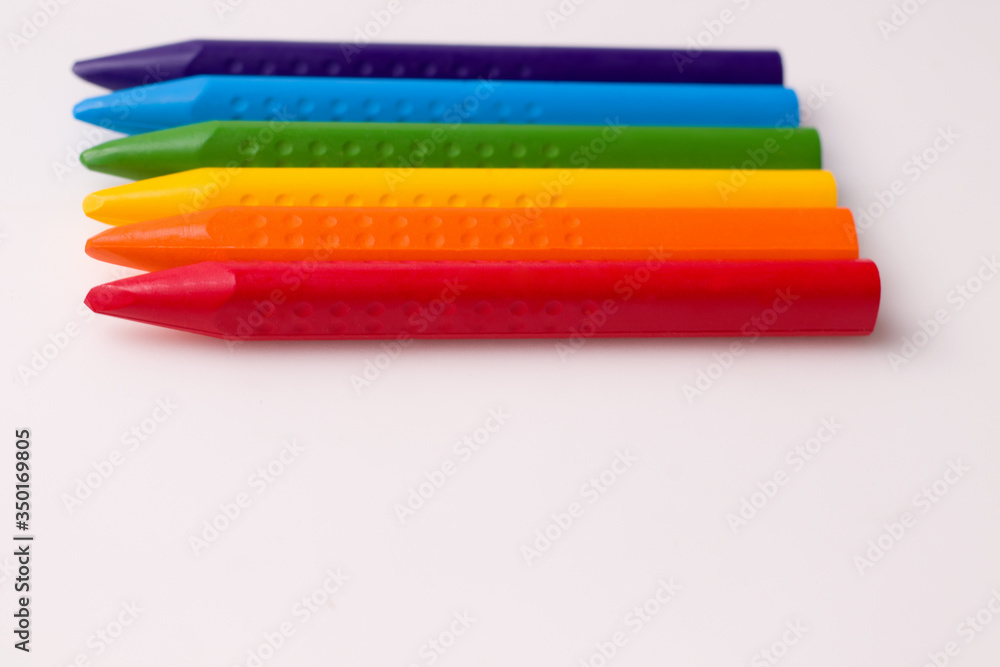 Chalks of different colors on white paper. Copy space. The concept of children's creativity and drawing lessons Chalks of different colors on white paper. Copy space. The concept of children's creativity and drawing lessons