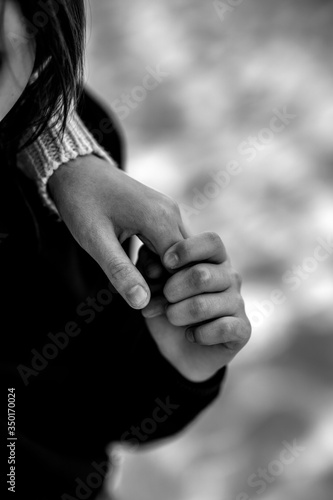 Close up cropped image loving tender older sister gently touch hands of little sister. Friendship and love concept between sisters. Black and white photo.