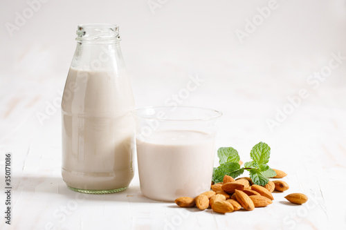 Almond milk in glass bottle with fresh almond nuts