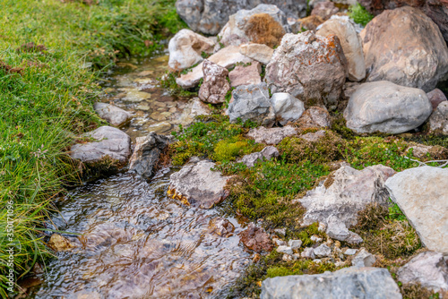 The small cute stream flows between green moss and stones in Fann mountains in Tajikistan