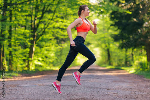 Young fit woman does running, jogging training in a park at summ