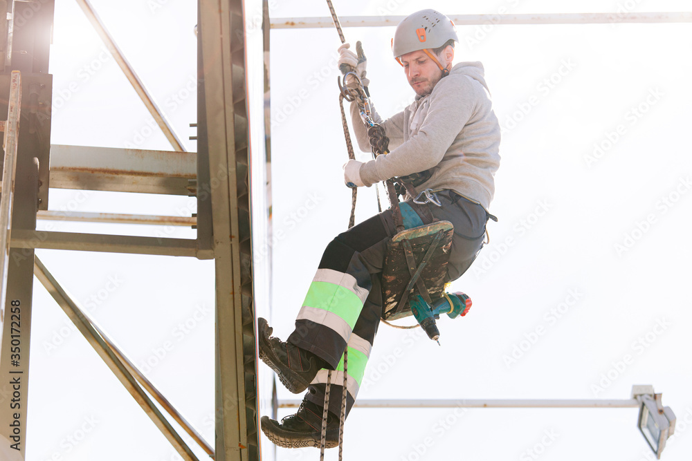 Industrial climber in helmet and overall working on height. Risky job. Professional worker Industrial climber in helmet and overall working on height. Risky job. Professional worker