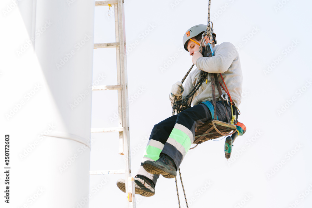 Industrial climber in helmet and overall working on height. Risky job. Professional worker