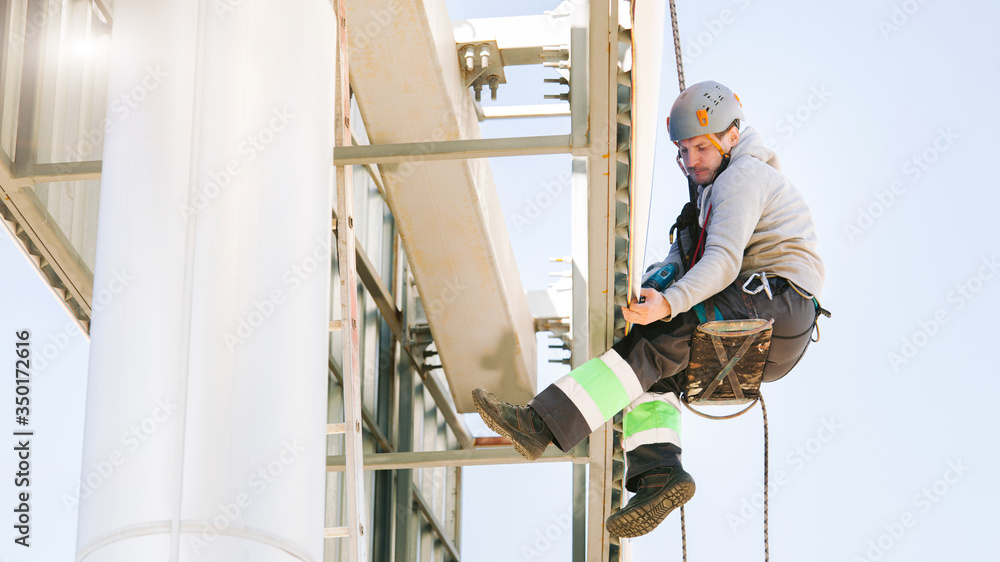 Industrial climber in helmet and overall working on height. Risky job. Professional worker