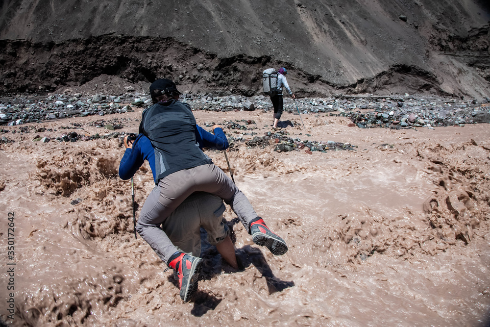 A man carries a woman on his back. Tourists at the foot of the mountain. Hiking. Lefestyle. A man carries a woman on his back. Tourists at the foot of the mountain. Hiking. Lefestyle.