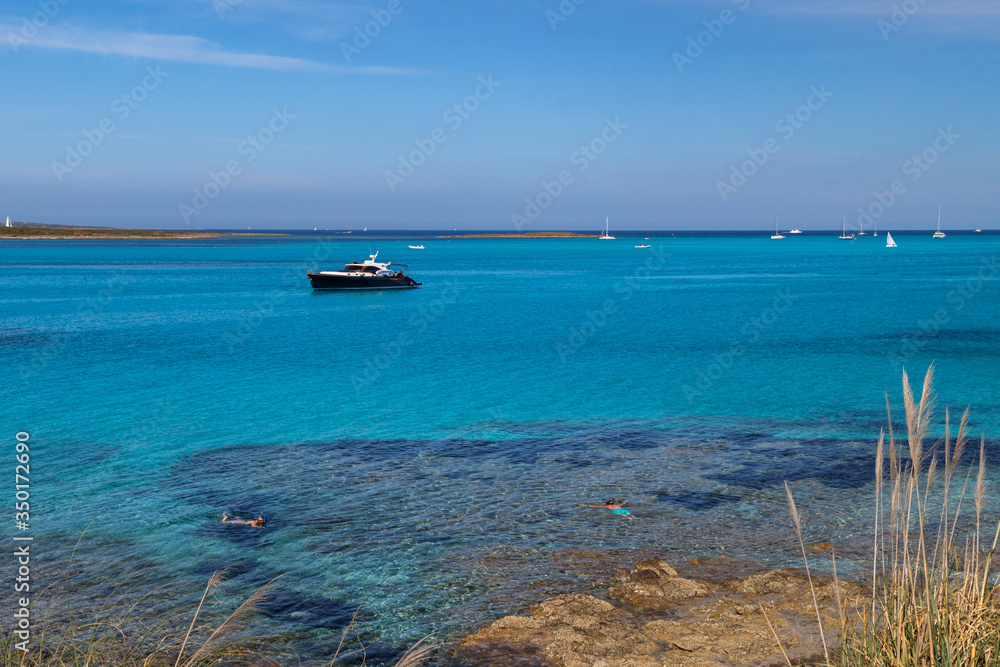 Fototapeta premium Seascape with two people snorkelling in the sea in the foreground, boats and yachts in the background. Active holidays in Sardinia, Italy.