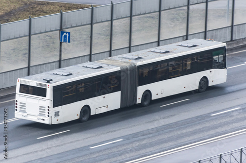 Double-articulated bus rides on the highway in the city.