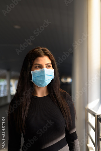 Young Indian woman thinking with mask for protection from corona virus outbreak at the footbridge