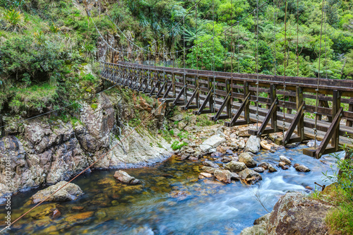 A wooden suspension bridge in a rocky river valley. Karangahake Gorge  New Zealand