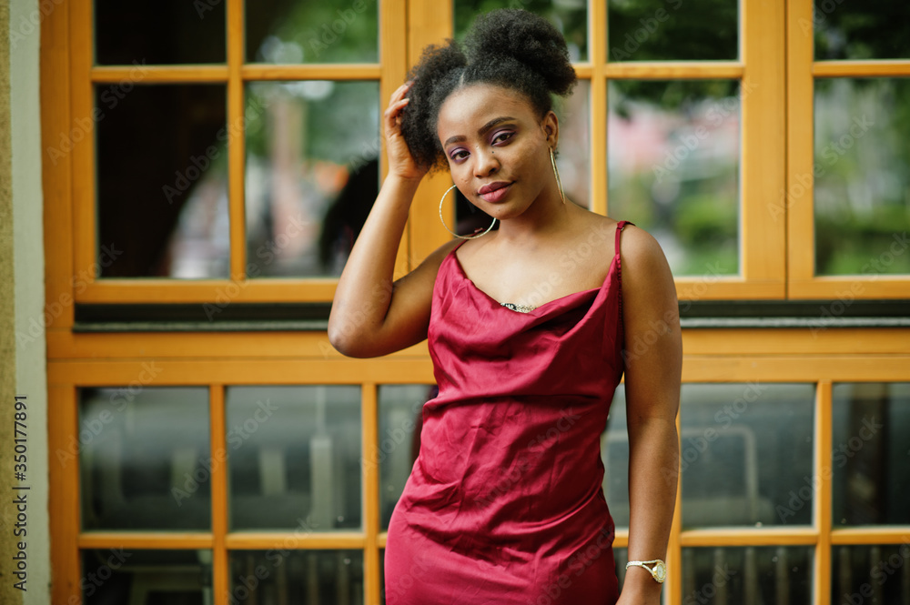 Portrait of a beautiful natural young African woman with afro hair. Black model in red silk dress.