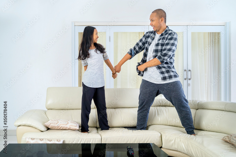 Obraz premium Father and child doing backpack kid dance on couch