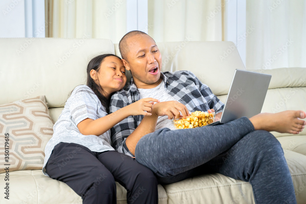 Father and child watching a movie on a laptop Father and child watching a movie on a laptop