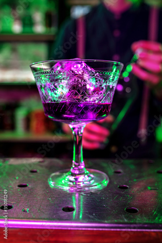 Close up of alcoholic cocktail, beverage, drink, prepared by professional barman in multicolored neon light. Entertainment, drinks, service concept. Modern bar, trendy neoned colors, copyspace.