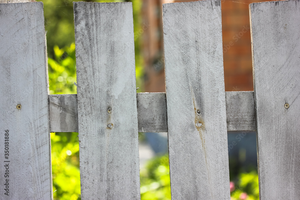 White wooden fence against the background of a garden and blossoming bushes in summer, life in a country house on vacation White wooden fence against the background of a garden and blossoming bushes in summer, life in a country house on vacation