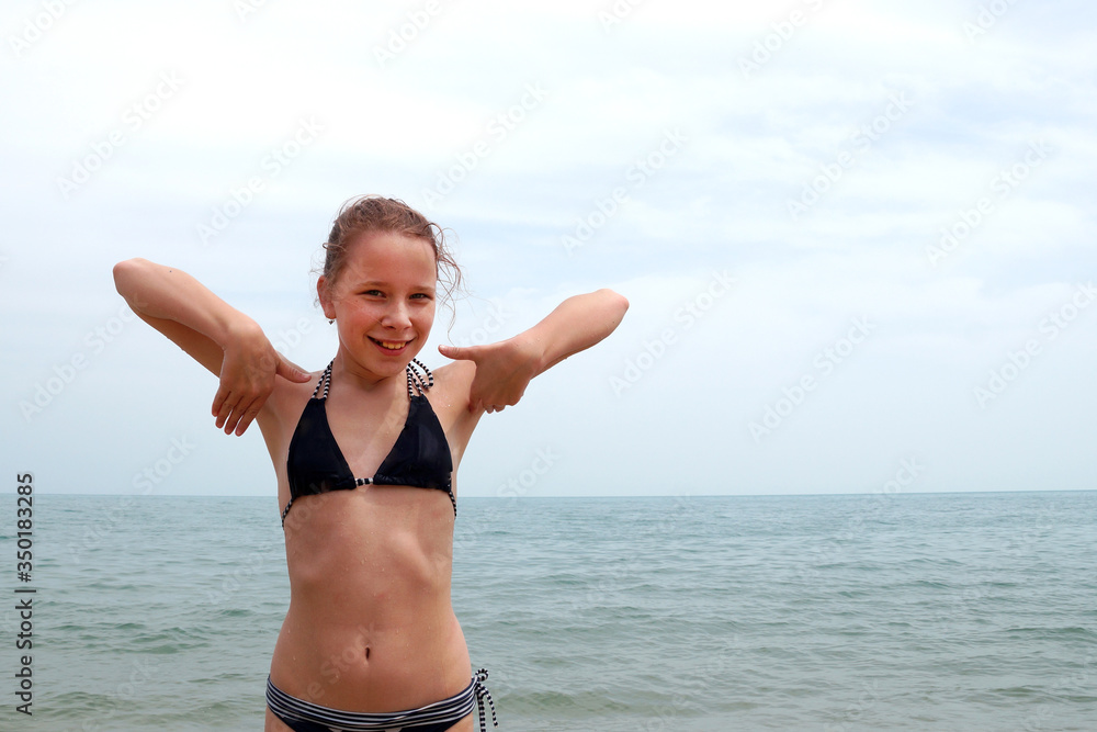 girl in a swimsuit at sea rejoices with hands up
girl in a swimsuit at sea rejoices with hands up