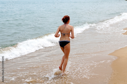  girl in a swimsuit runs along the sea 