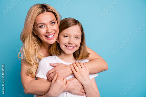 Photo of two people beautiful mommy lady little daughter blonds hugging best friends piggyback holding arms spend time together wear casual white s-shirts isolated blue color background