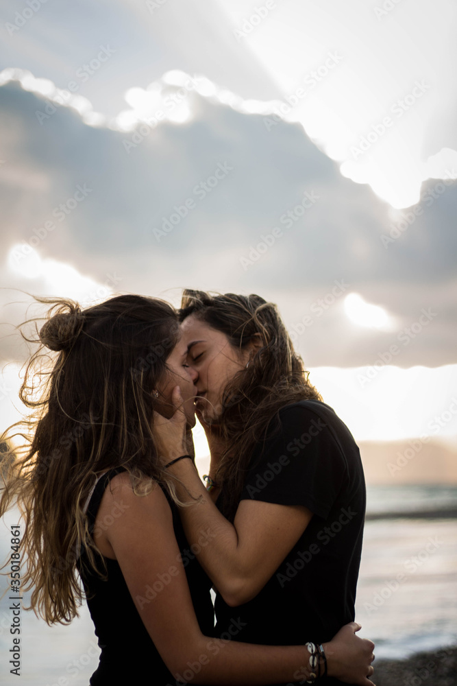 Pareja de dos chicas morenas jóvenes que son novias lesbianas besándose en  la playa junto al mar Stock-Foto | Adobe Stock
