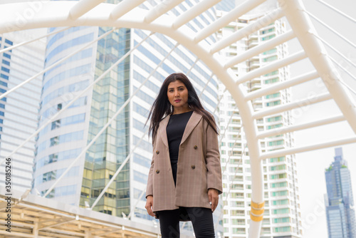 Young beautiful Indian businesswoman at the skywalk bridge photo