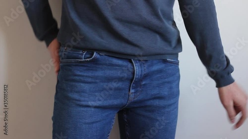 Man searches for money in his pockets and finds 100 dollars.  European man in blue jeans looks for money in his pockets and finds 100 dollars in his back pocket and shows them.