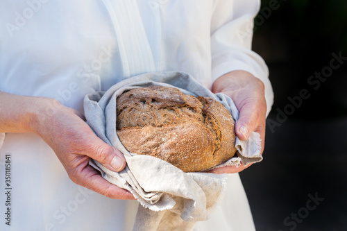 Fresh loaf of homemade rye bread in woman hands