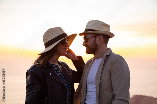 Lovers with hats looking at each other in the sunset
