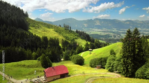 Flying over beautiful mountains with the view to the valley, Alpen in Allgäu, Deutschland,  with hikers walking on green meadows to an inn, enjoying their recreational nature vacation  photo