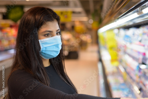 Face of young Indian woman with mask shopping with distance at the supermarket