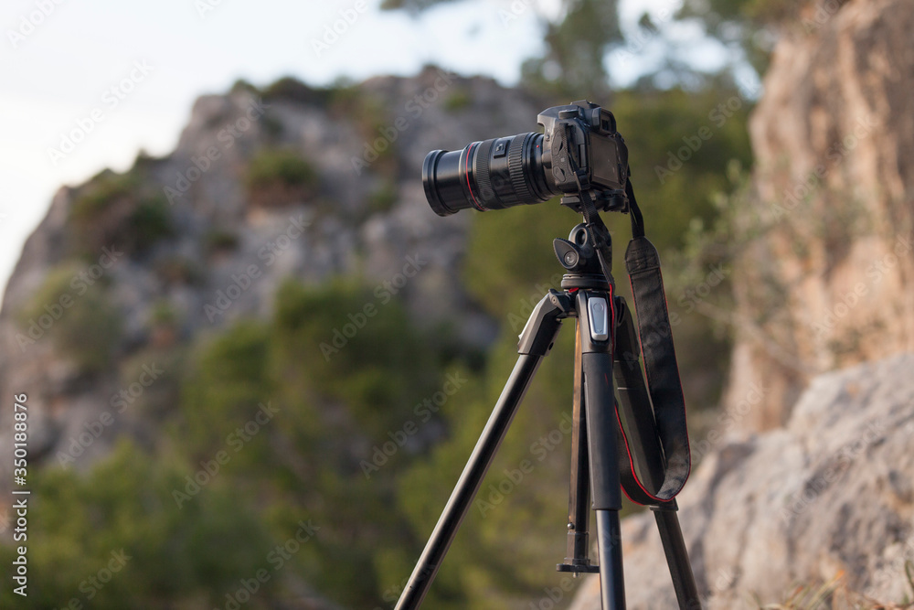 A photo camera on a tripod in mountainous background at sunset. Mallorca.Spain. A photo camera on a tripod in mountainous background at sunset. Mallorca.Spain.