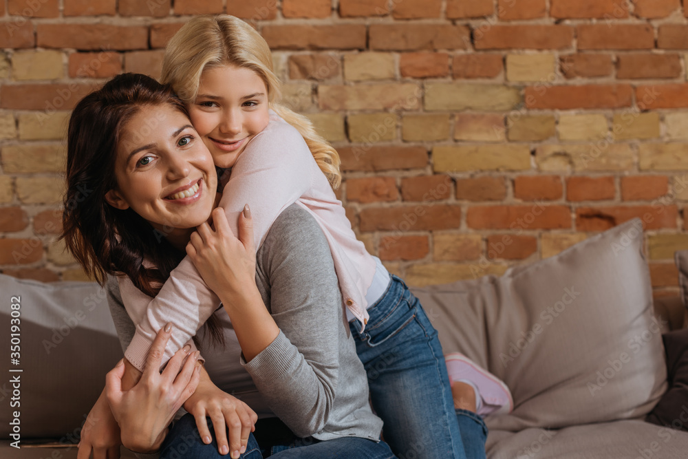 Happy child embracing smiling mother on sofa Happy child embracing smiling mother on sofa