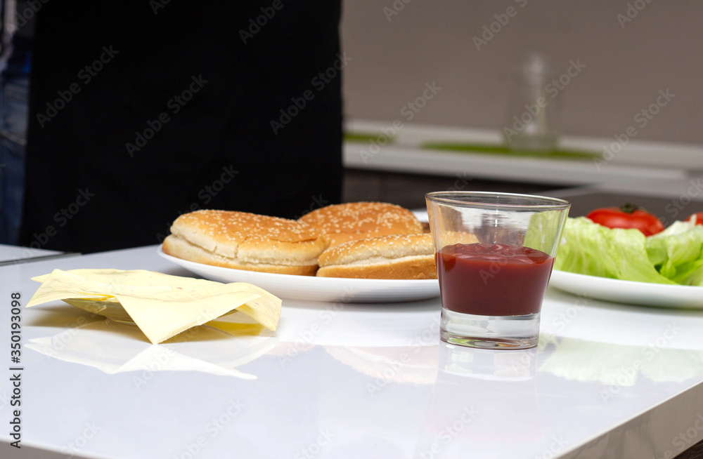 The ingredients are in the kitchen in the form of cheese, salad, tomato and burger rolls. Cooking Burgers at Home, Background The ingredients are in the kitchen in the form of cheese, salad, tomato and burger rolls. Cooking Burgers at Home, Background