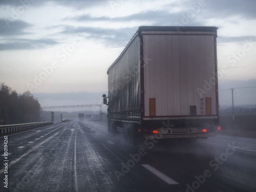 A truck wagon rides on a highway with poor visibility where it rains and fog, background. Bad Road Safety Concept, copy space