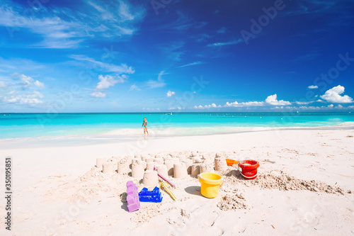 Fototapeta Naklejka Na Ścianę i Meble -  Sandcastle at white sandy beach with plastic kids toys and sea background