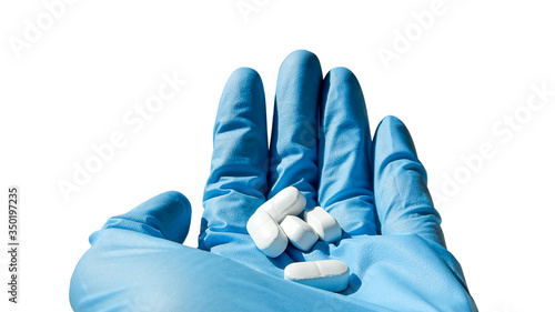 hand in a blue medical glove holds a white pill on a white background