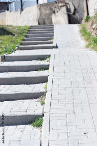 Stone steps on the sidewalk to climb the upper road © donikz
