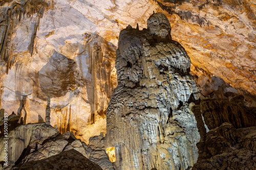 Massive stalagmite in a cave colored grey by impurities