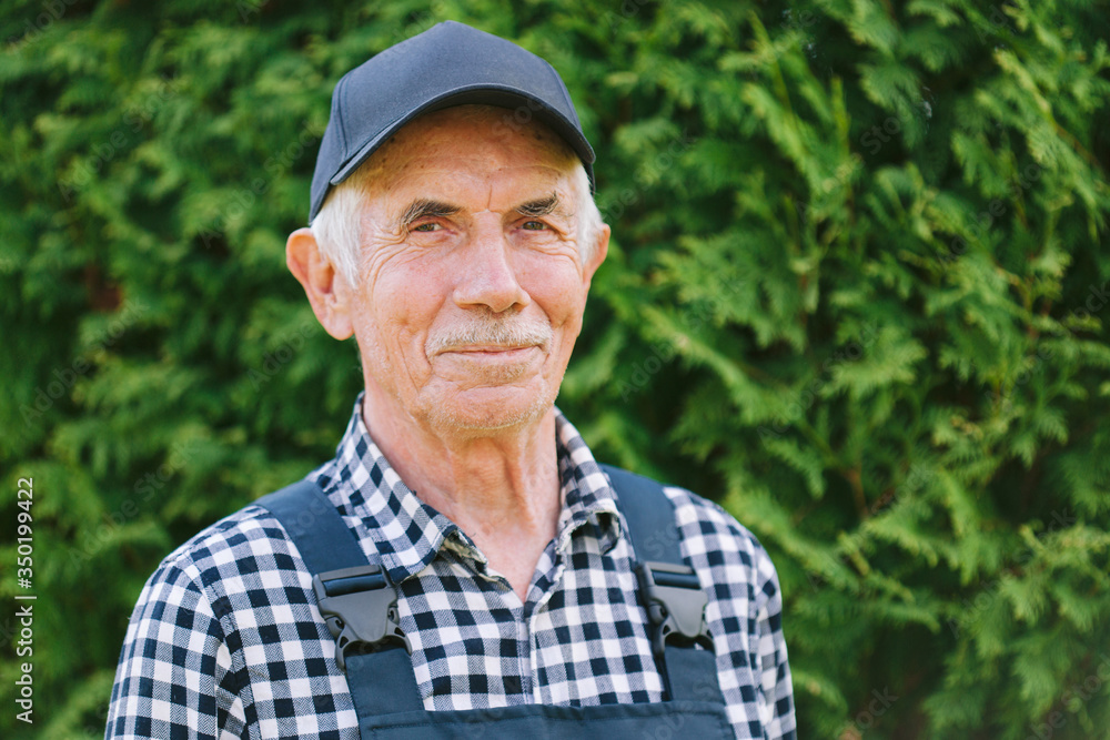 Senior professional worker in overall and cap. Aged farmer. Old craftsman. Close up
