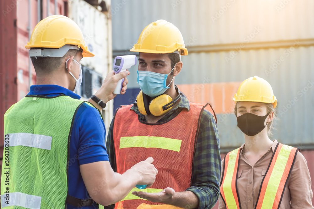 Worker is checking fever of his colleagues Worker is checking fever of his colleagues