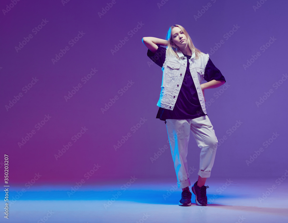 Cute teen girl dancing hip-hop in stylish black and white clothes, in a Studio with neon lighting. Dance color poster. Cute teen girl dancing hip-hop in stylish black and white clothes, in a Studio with neon lighting. Dance color poster.