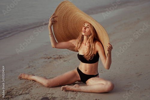 Obraz na płótnie portrait of blonde girl wearing big straw summer hat enjoying sunset w salonie