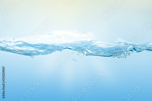 Water splash on blue background. Aqua flowing in waves and creating bubbles. Drops on the water surface feel fresh and clean.