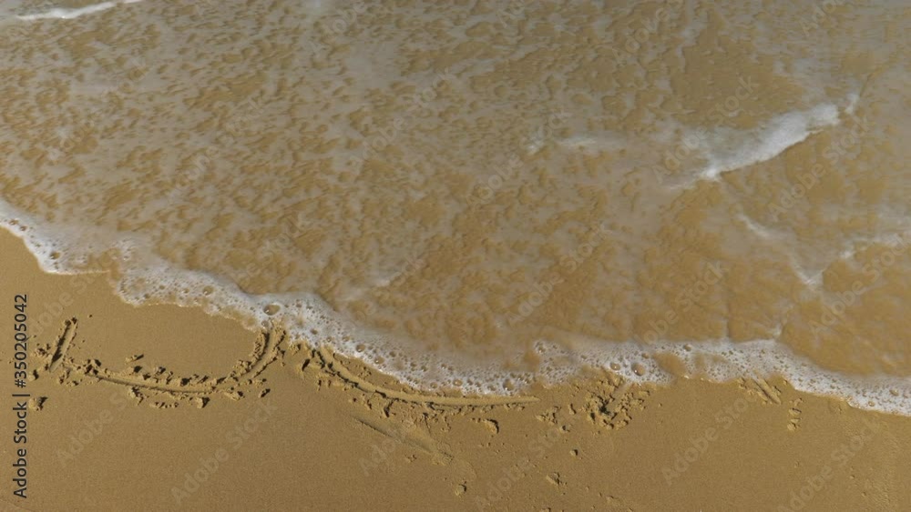 sea wave erases the inscriptions written on the sand. word sea. Slow motion. sea wave erases the inscriptions written on the sand. word sea. Slow motion.